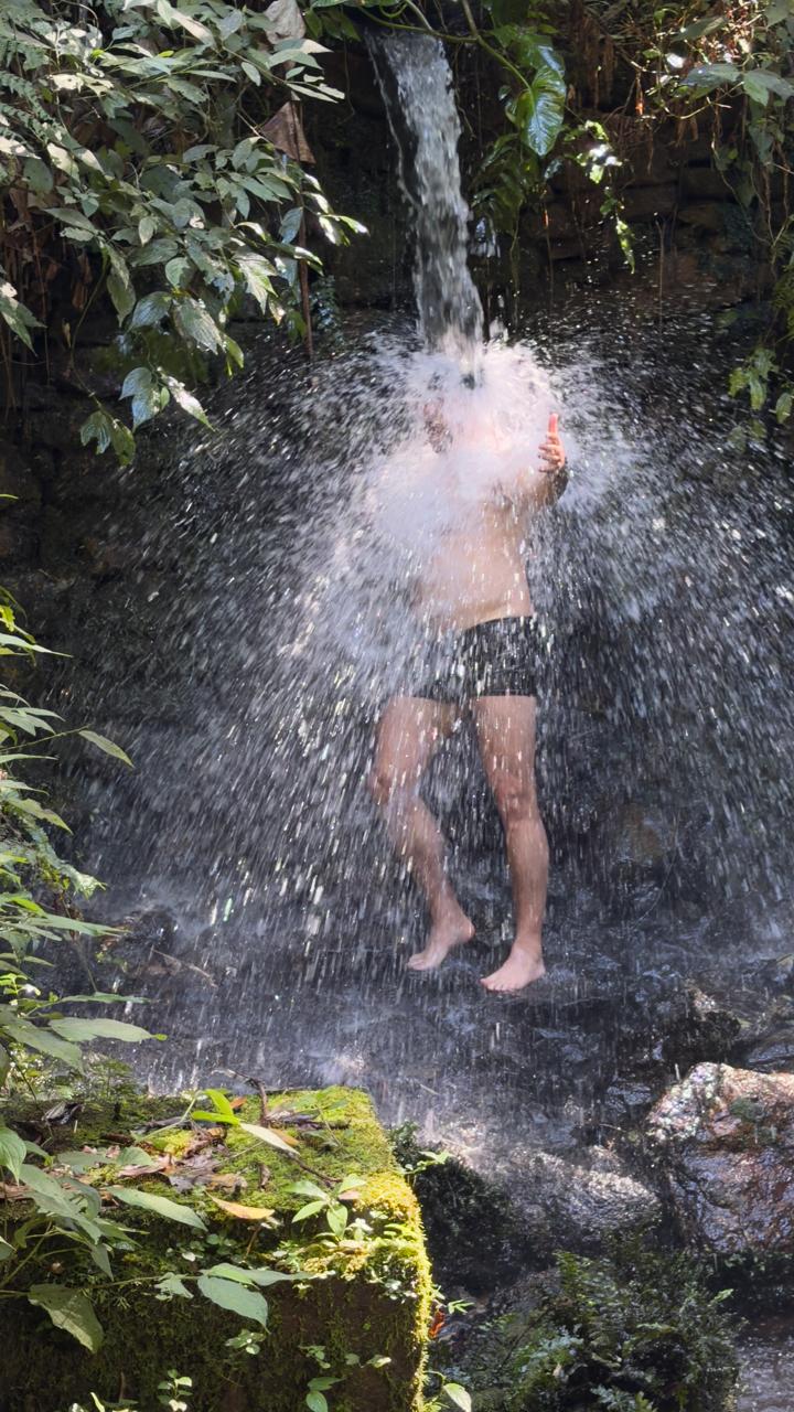 Pessoa sob a queda d'água da cachoeira